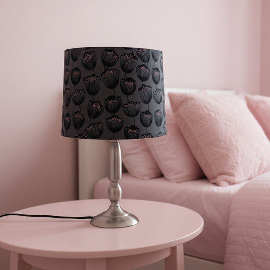 Table lamp with a black floral patterned shade on a white surface.