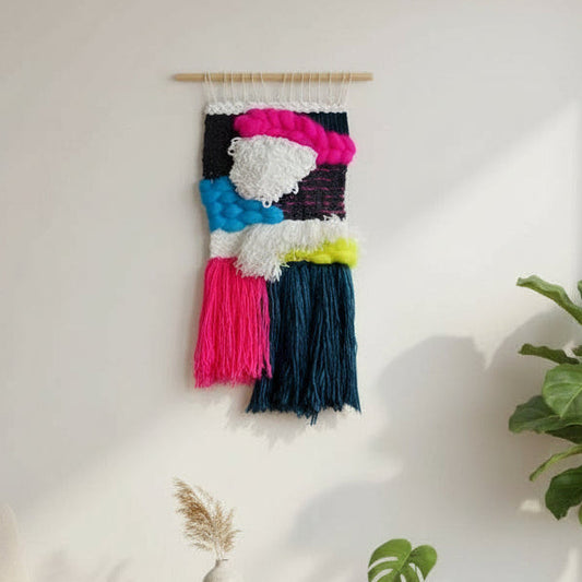 Modern living room with a colorful wall hanging, white armchair, and potted plants.