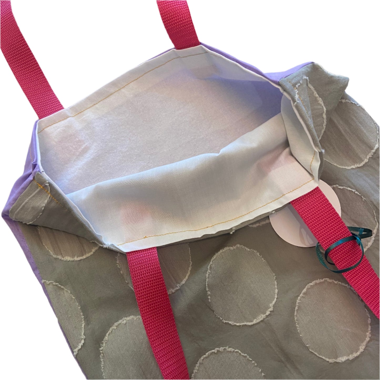 Grey fabric with circular patterns and a bright pink strap on a white background