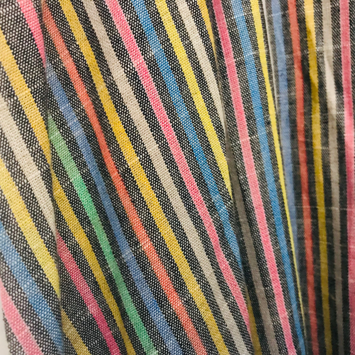 A close-up of a striped textile with diagonal bands of black, yellow, blue, pink, green, and white.