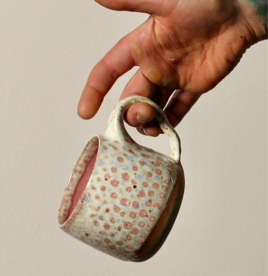 Hand holding a ceramic mug with floral pattern against a plain background