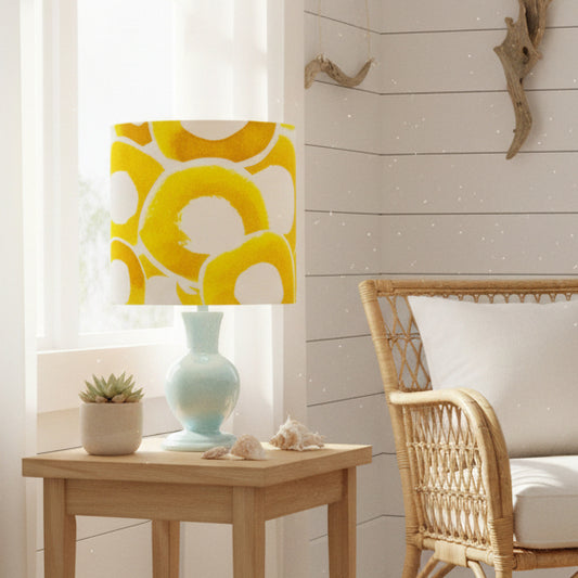 Lamp with a yellow and white patterned shade on a light blue base against a white background
