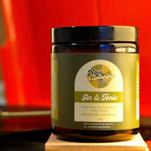Jar of 'Gin & Tonic' candles with a label on a wooden block against a red background