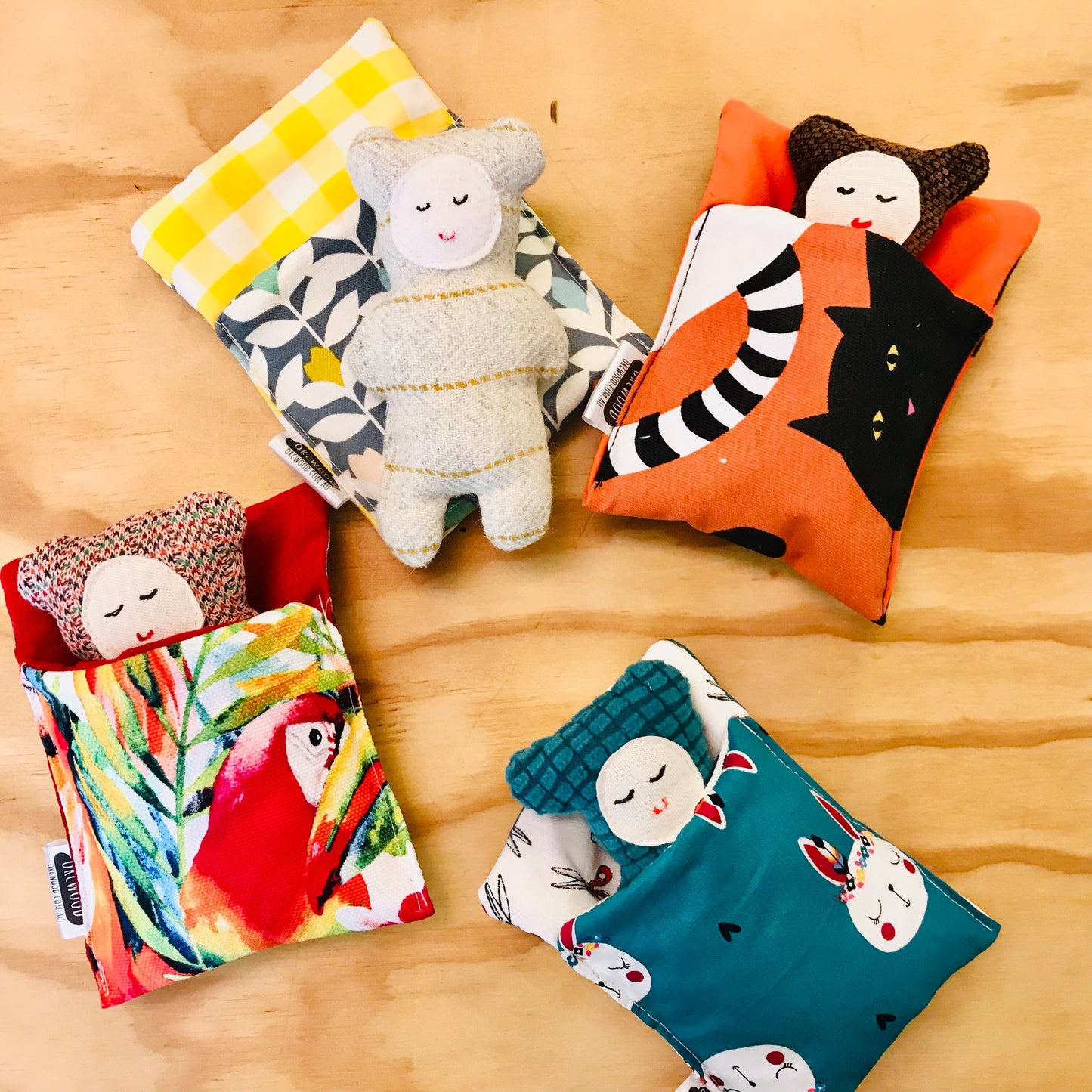 Colorful fabric bags with plush toys on a wooden surface