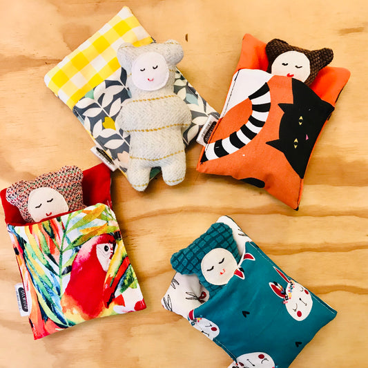 Colorful fabric bags with plush toys on a wooden surface