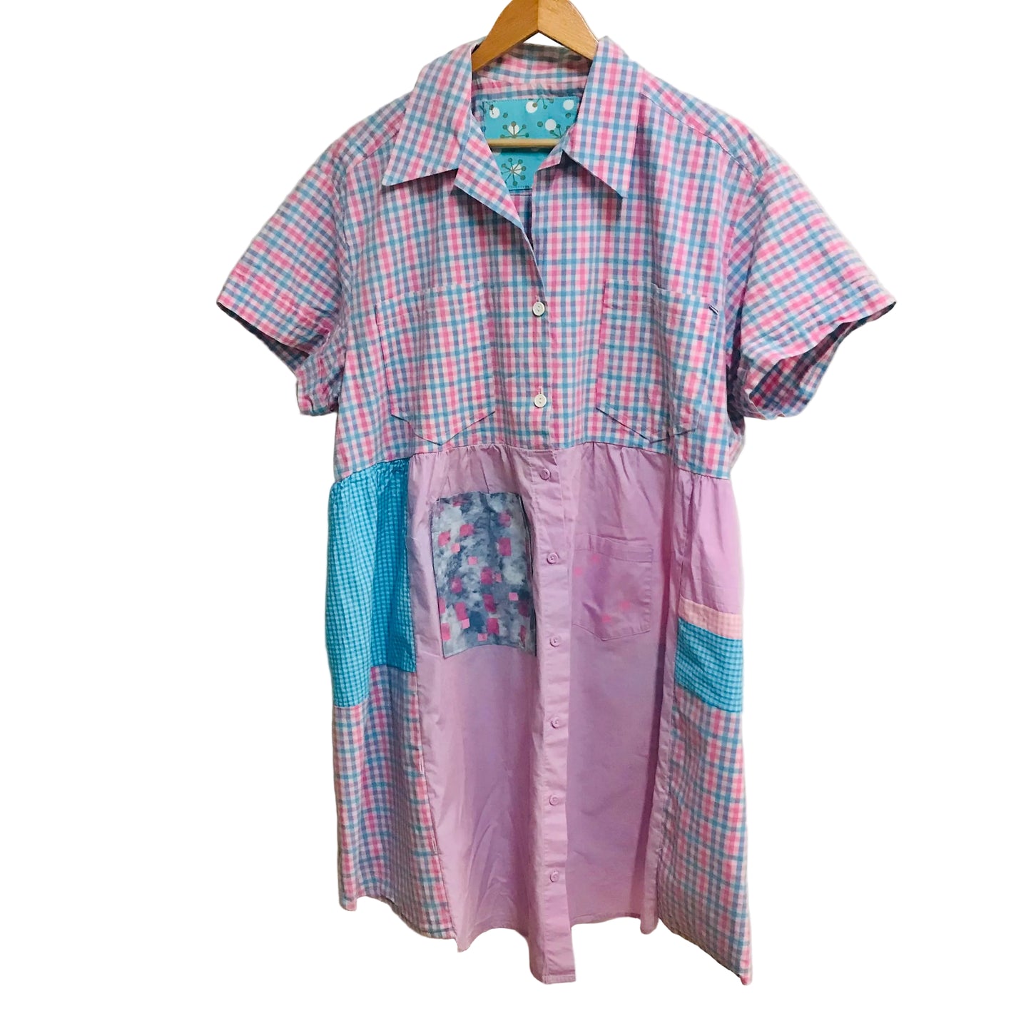 Plaid and patchwork dress on a hanger against a plain wall