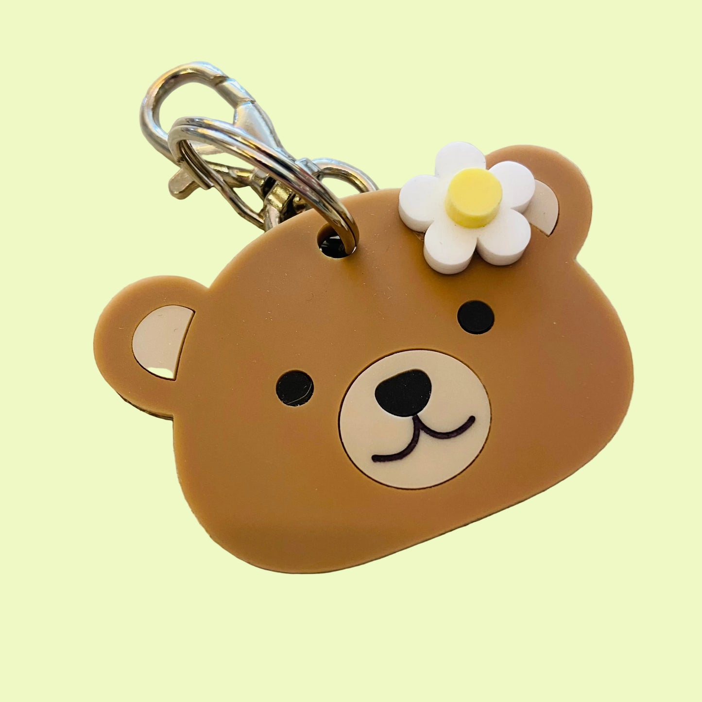 Brown bear-shaped keychain with a flower on a textured surface