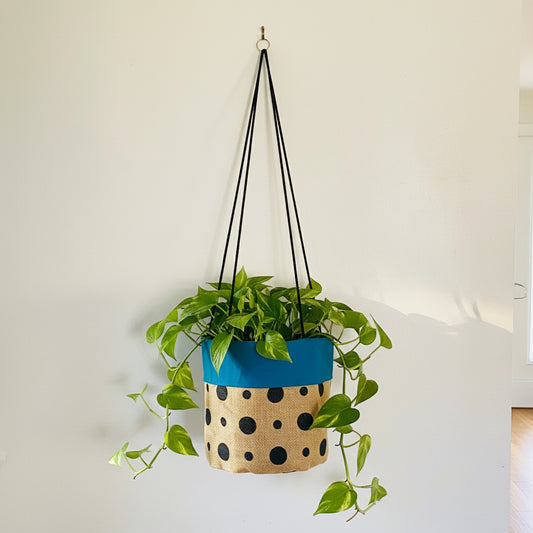 hanging planter with blue top and polka dot pattern on beige base, hanging against a plain background.