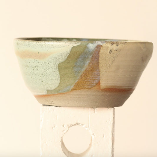 Ceramic wall sconce with a textured design on a neutral background