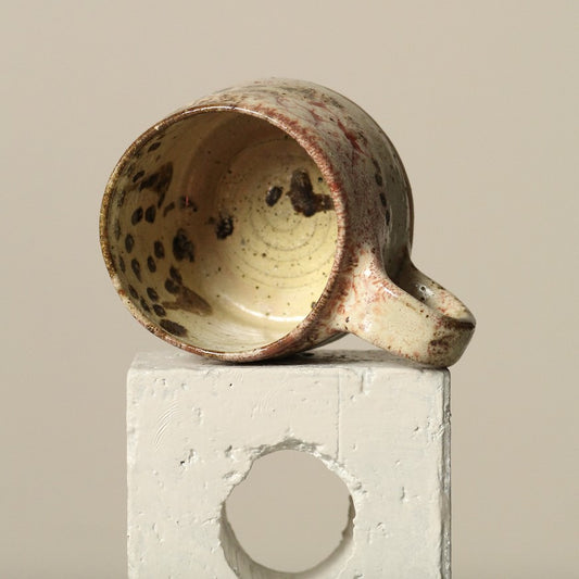 Handmade ceramic mug with speckled design on a neutral background