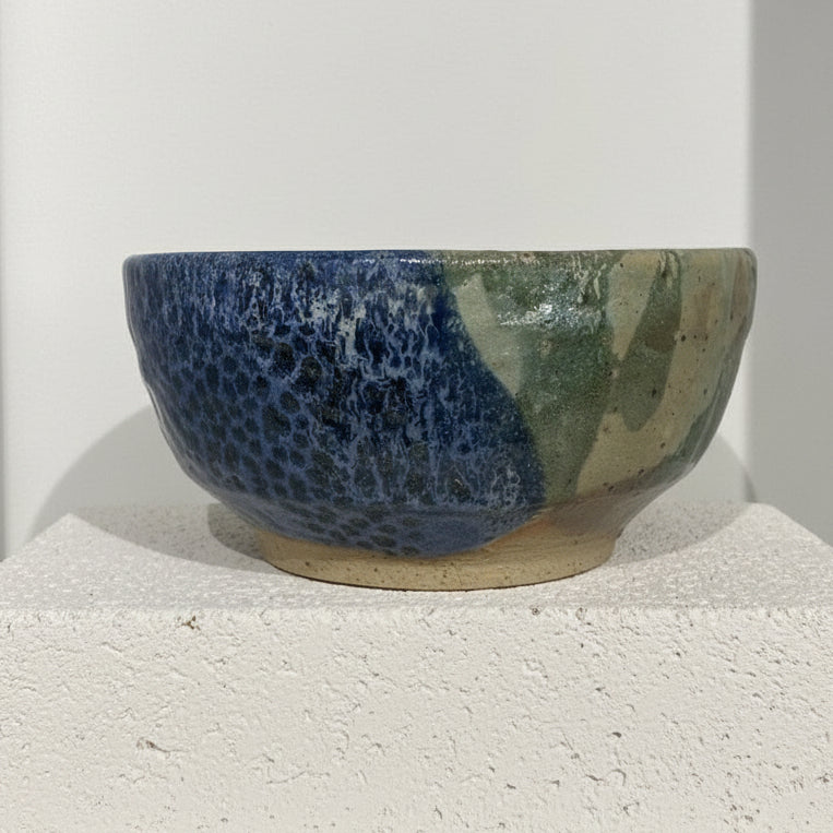 Ceramic bowl with blue and green glaze on a white background