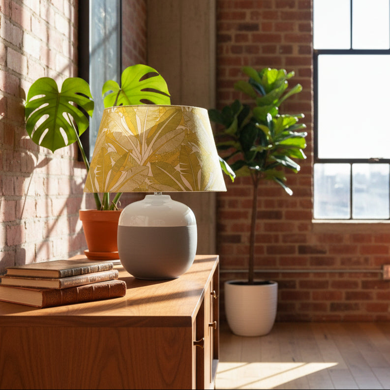 Table lamp with a green leaf-patterned shade sitting on a sideboard in a loft
