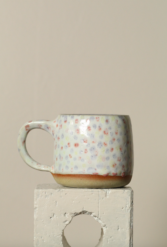 Ceramic mug with dot pattern on a beige background