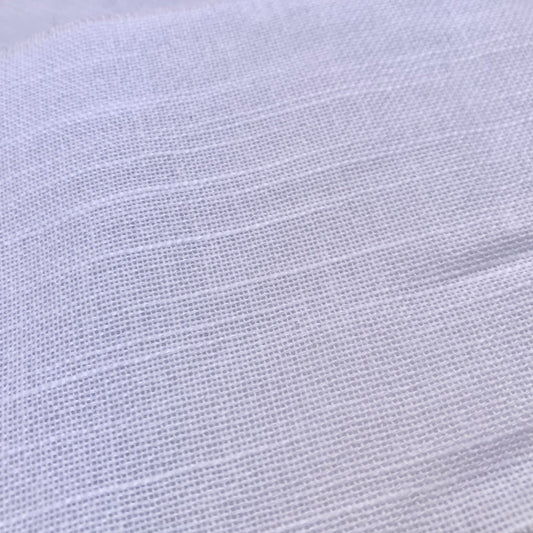 A close-up of white textured fabric with a fine woven pattern and soft horizontal folds.