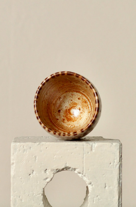 Ceramic bowl with brown speckles on a textured white surface