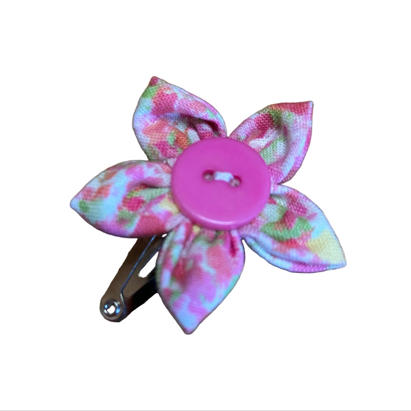 Floral hair clip with a pink button center on a wooden surface