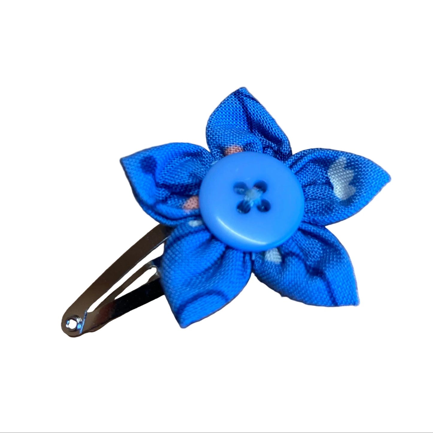 Blue flower-shaped hair clip with a button center on a wooden surface