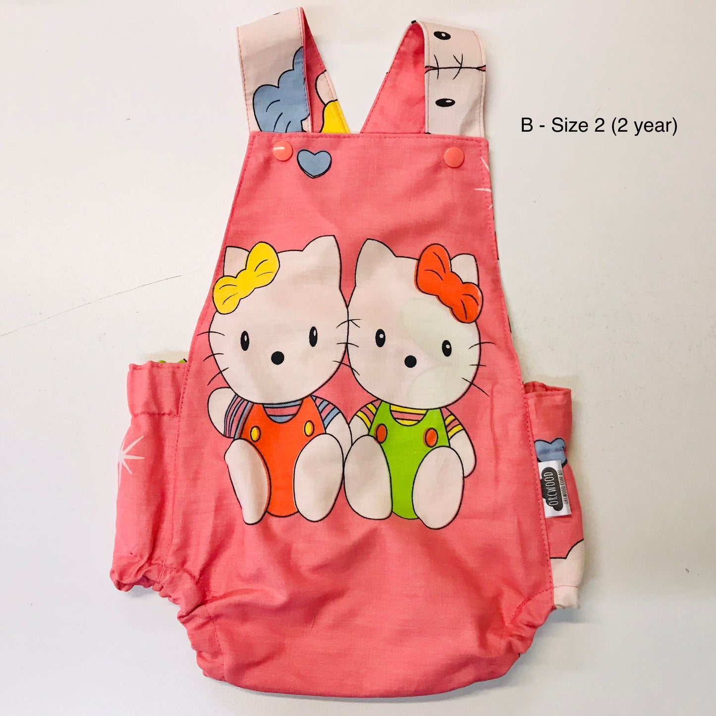 Pink children's romper with cartoon characters on a white background