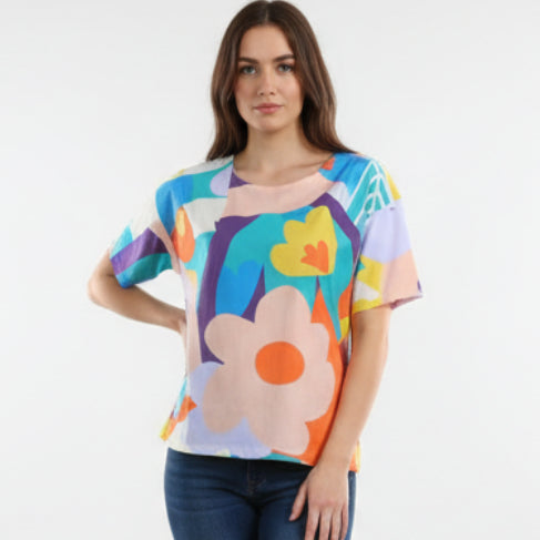 Colorful floral-patterned shirt on a mannequin against a brick wall.