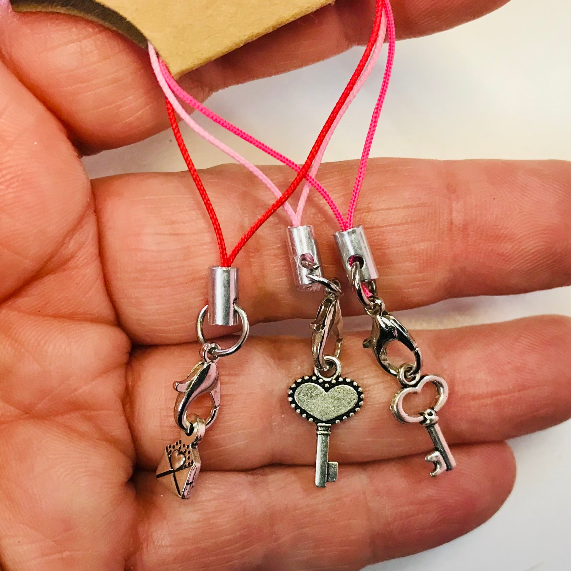 Three key-shaped charms on strings held in a hand