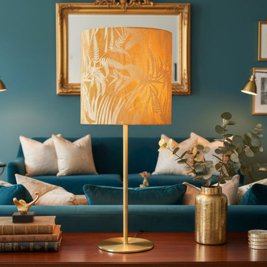 Table lamp with a gold leaf-patterned shade on a white background