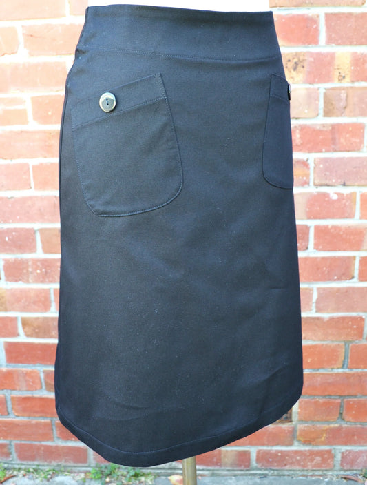 black skirt with a button on a mannequin against a brick wall.