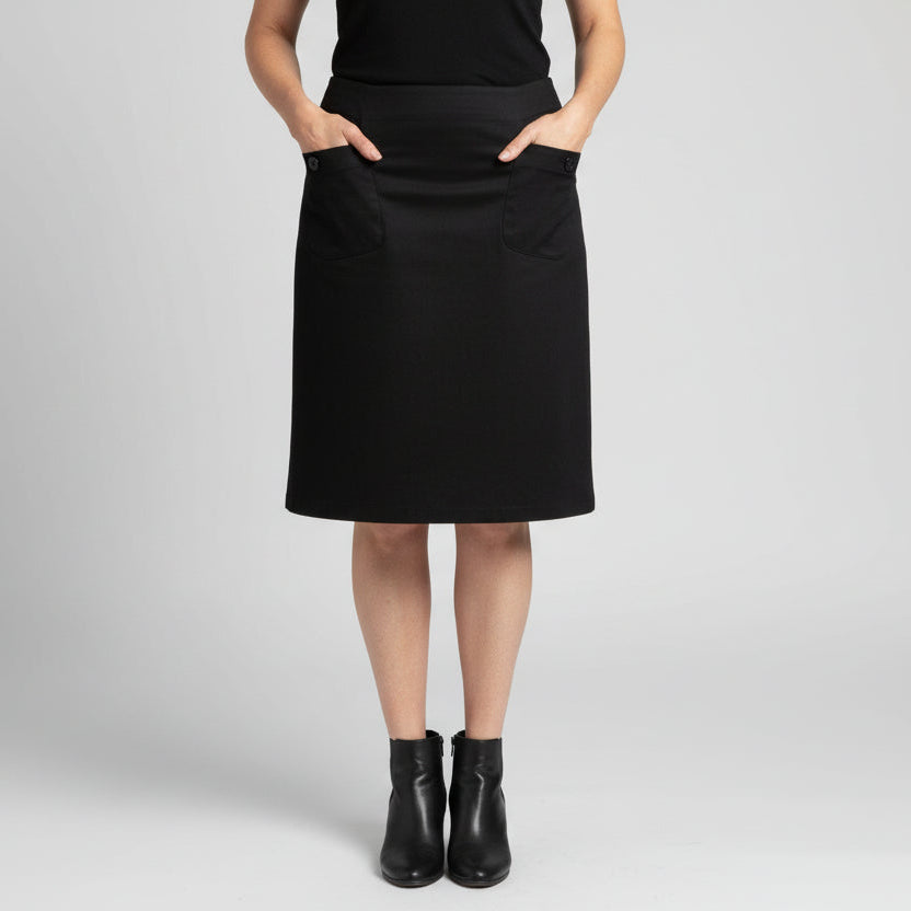 Person wearing a black skirk in front of a brick wall.