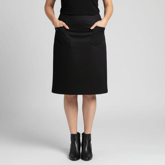 Person wearing a black skirk in front of a brick wall.