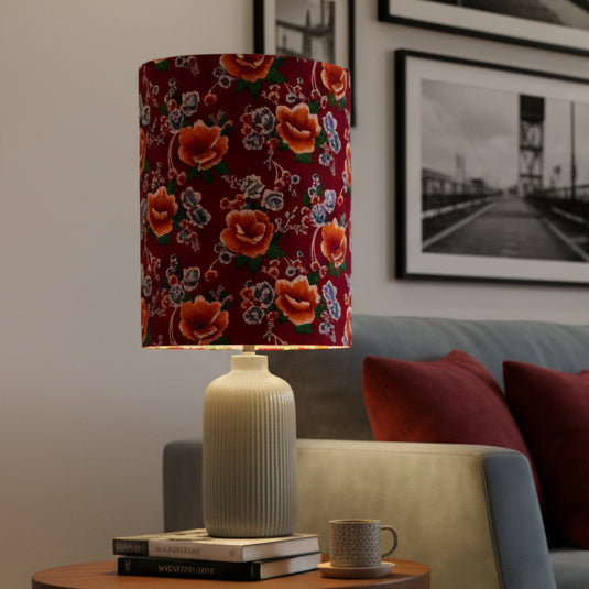 A table lamp with a cylindrical red floral fabric shade and a ribbed gray ceramic base