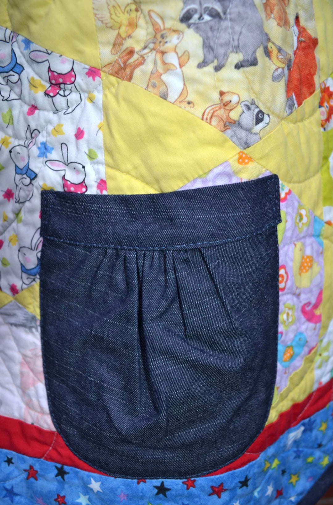 Dark blue denim pocket detail on a colorful quilted jacket with cartoon characters