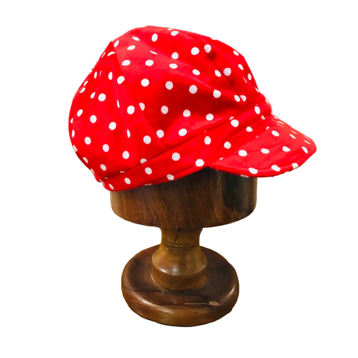 Red polka dot cap on a wooden mannequin head against a neutral background