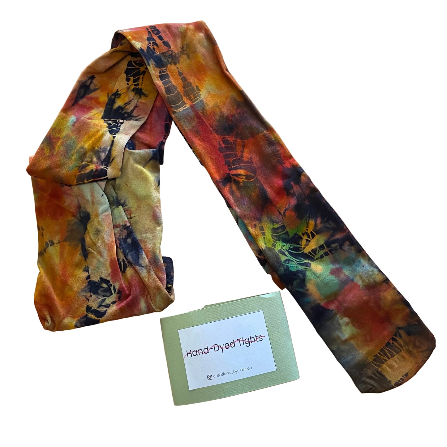 Hand-dyed tights with a tie-dye pattern on a wooden surface, accompanied by a label reading 'Hand-Dyed Tights'.