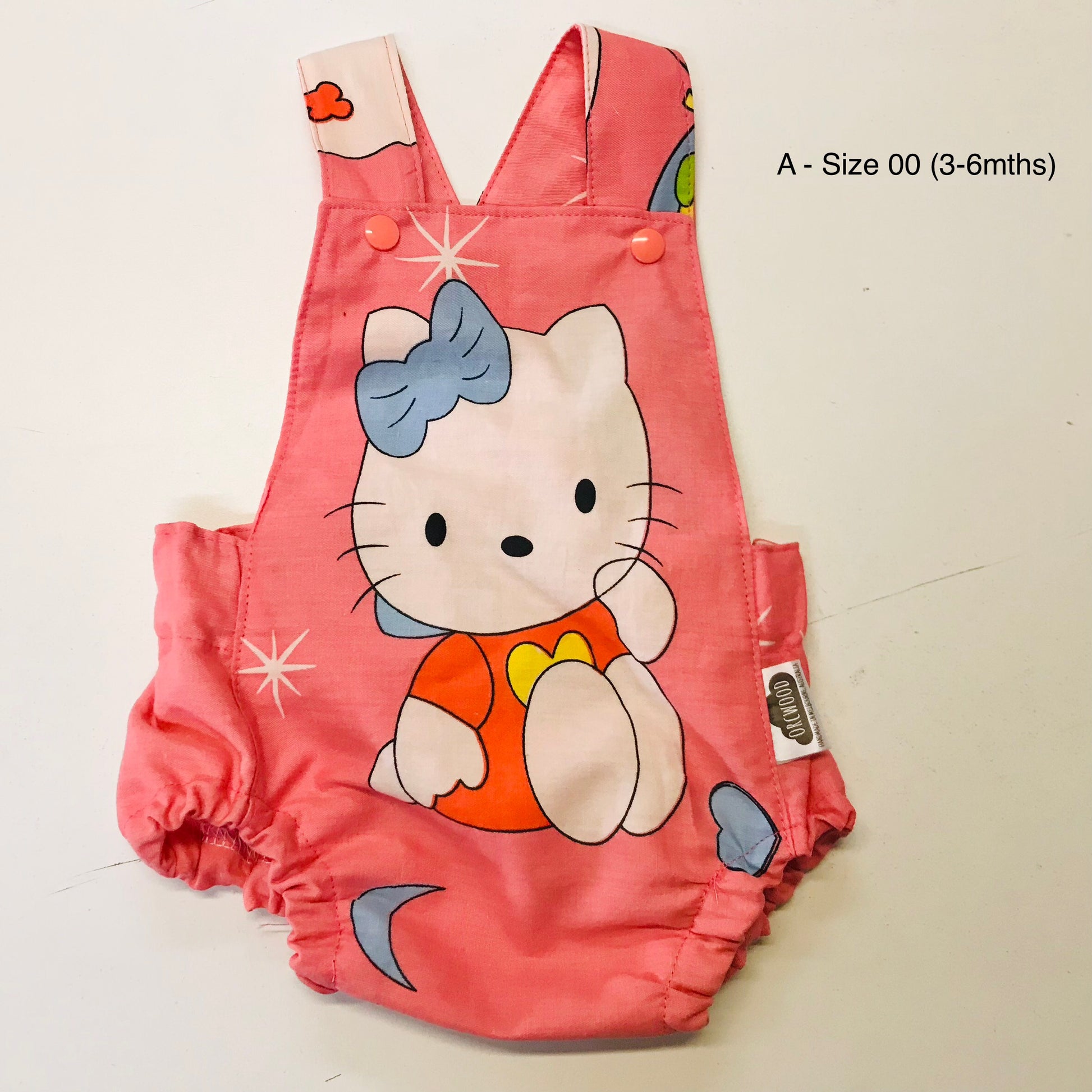 Pink baby romper with cartoon character on a light beige background