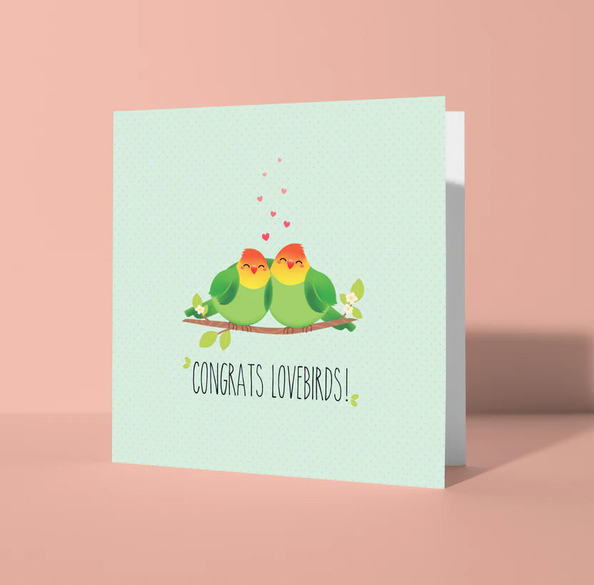 Greeting card with two birds on a branch and 'Congrats Lovebirds!' text on a light blue background.