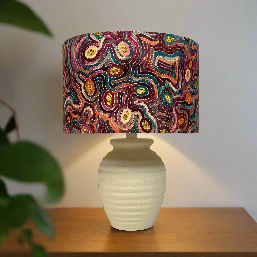 a cream stone looking table lamp with an indigineous shade