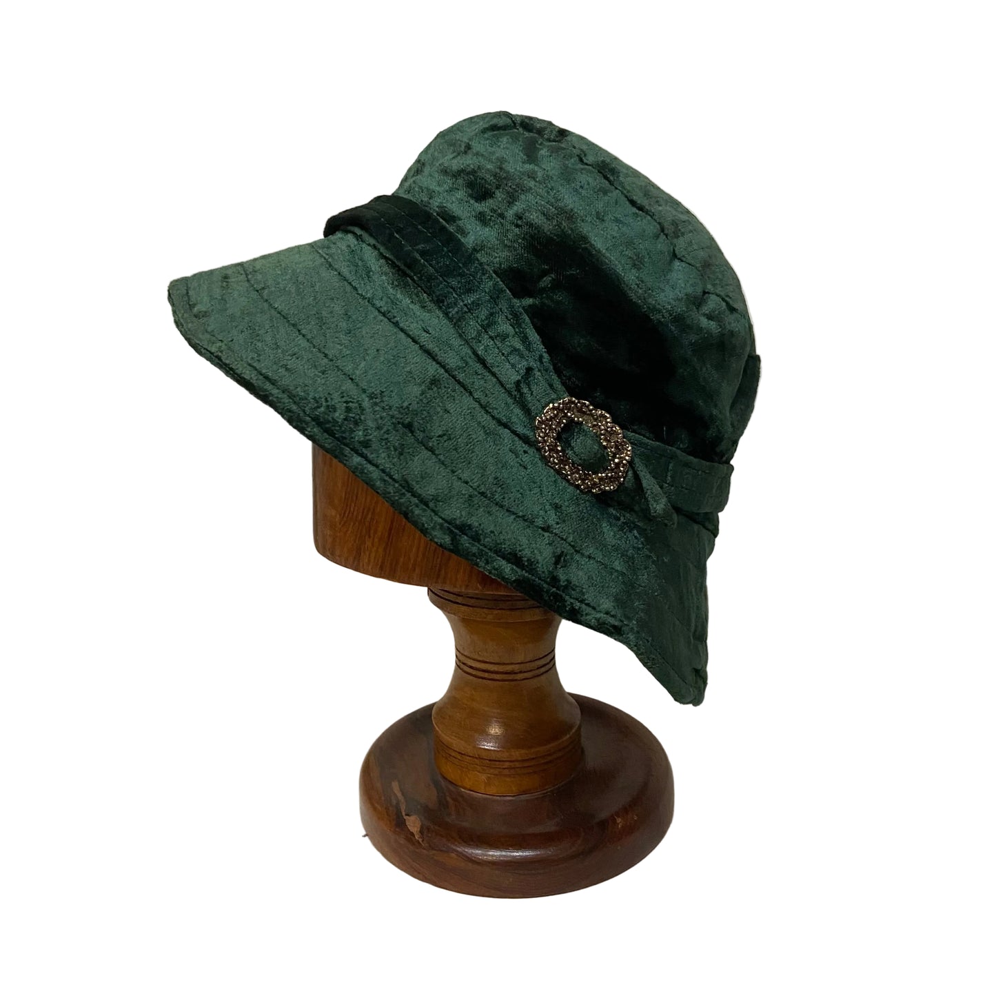 Green velvet hat on a wooden mannequin head against a plain background