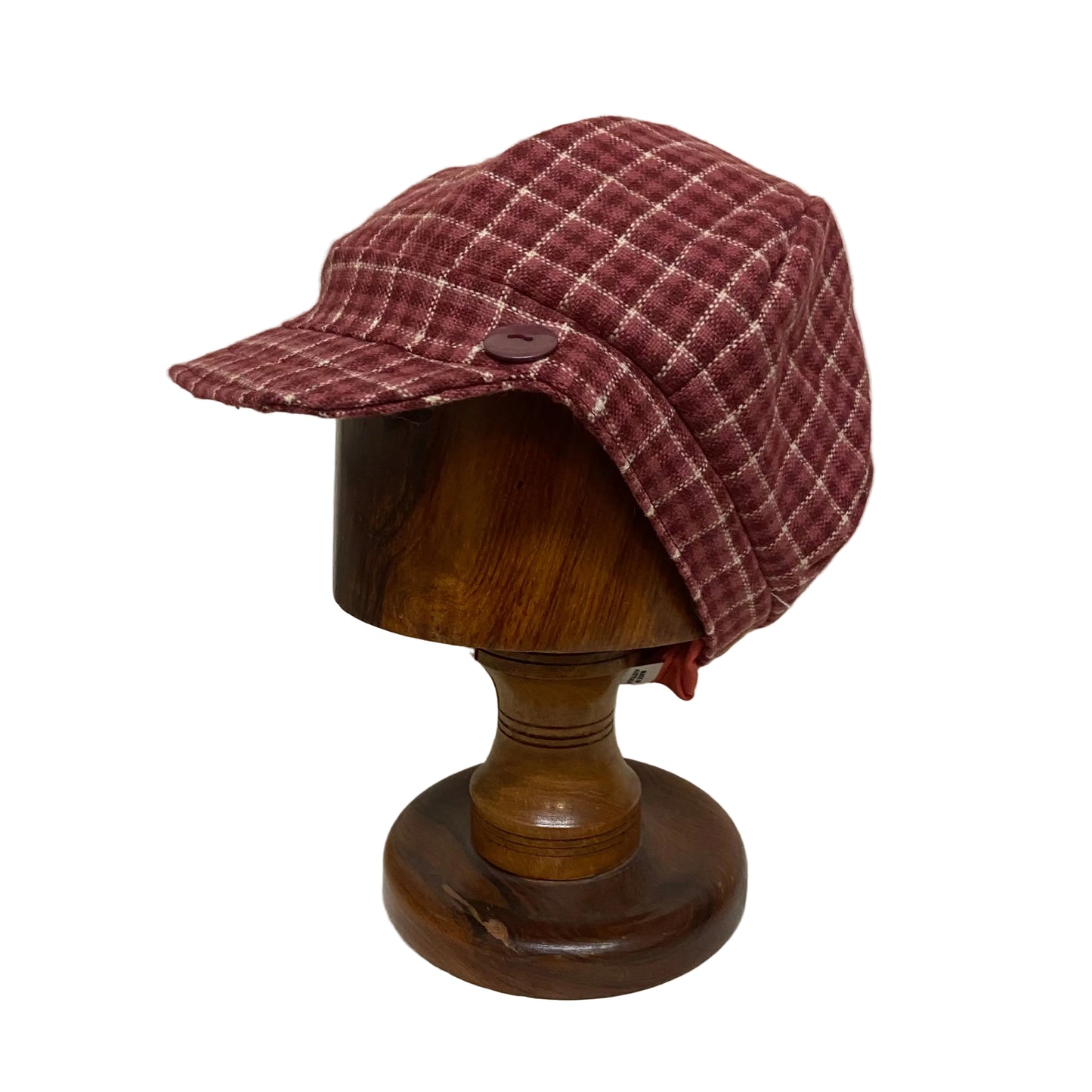 Plaid patterned cap on a wooden mannequin head against a plain background