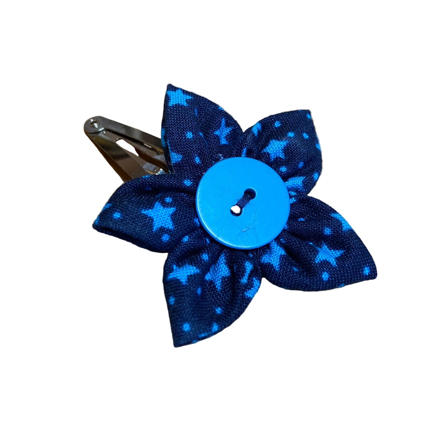 Blue polka dot bow hair clip with a button on a wooden surface