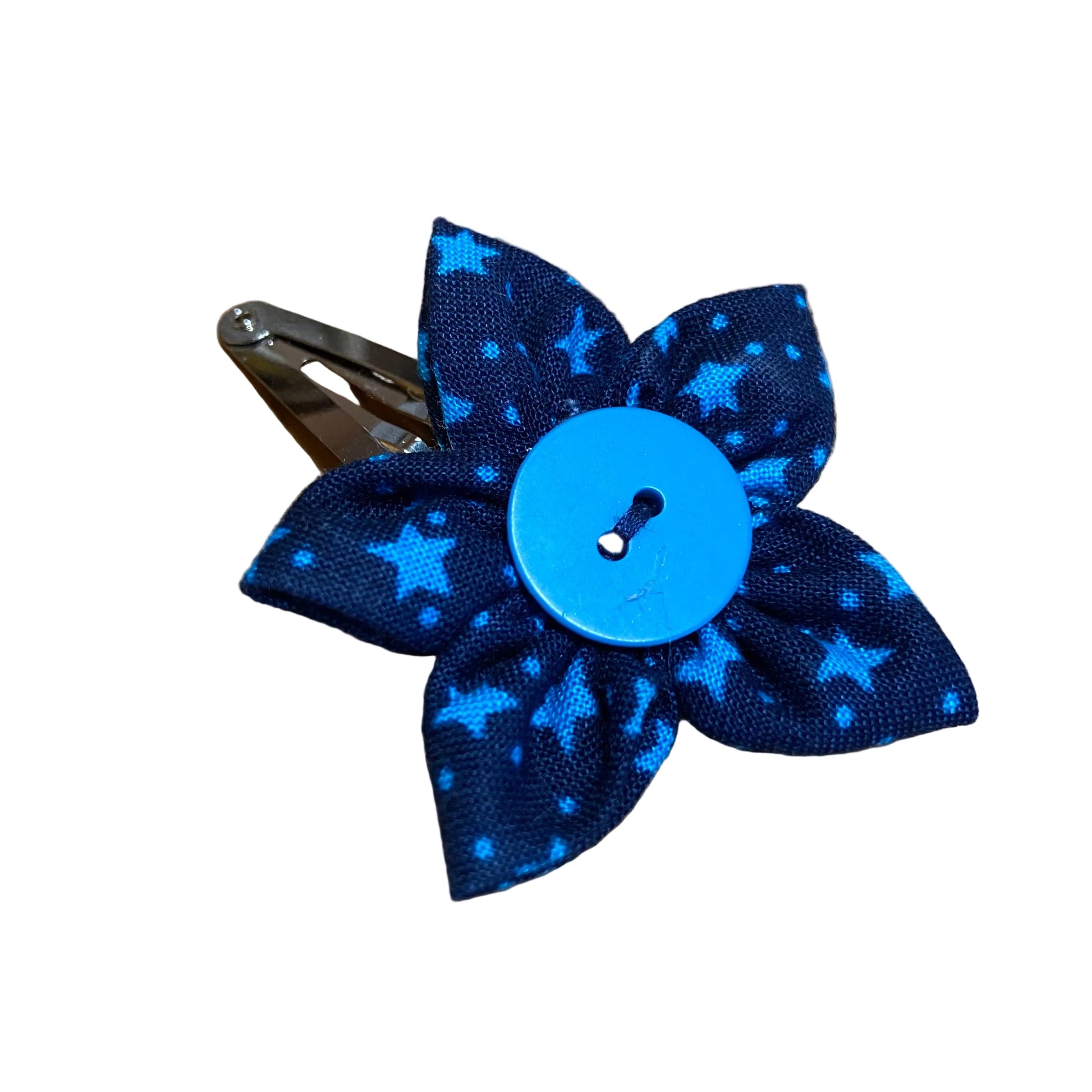 Blue polka dot bow hair clip with a button on a wooden surface