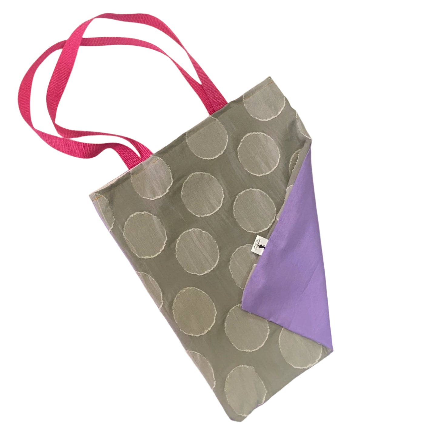 Gray tote bag with textured spots and bright pink straps and a purple back on a white surface