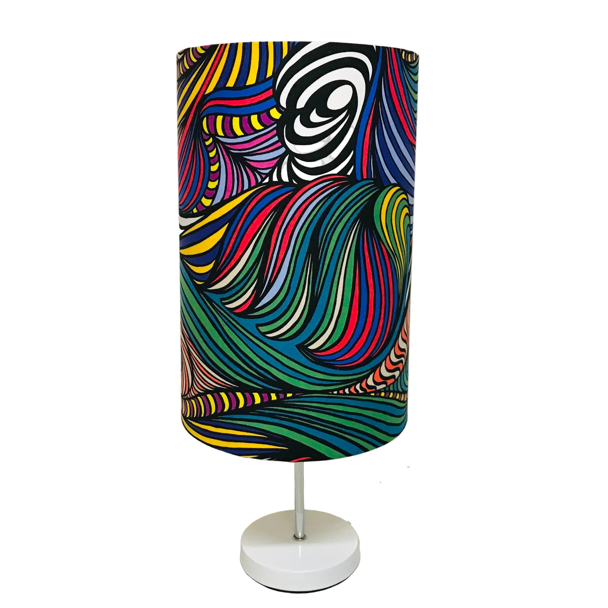 A table lamp with a colorful cylindrical shade featuring a psychedelic, swirling line pattern in multiple bright colors, supported by a white metal stand and a round white base.