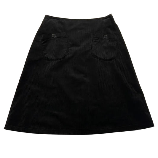 Black skirt on a white table with a pen and paper in the background