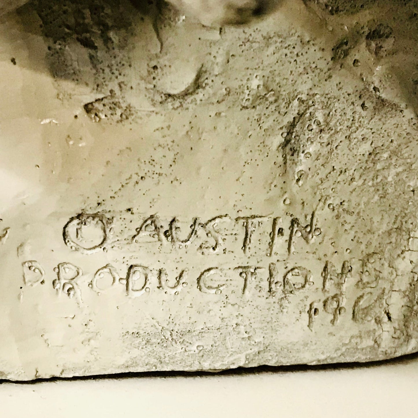 Close-up of a stone sculpture with 'O Austin Production 1968' engraved on it.