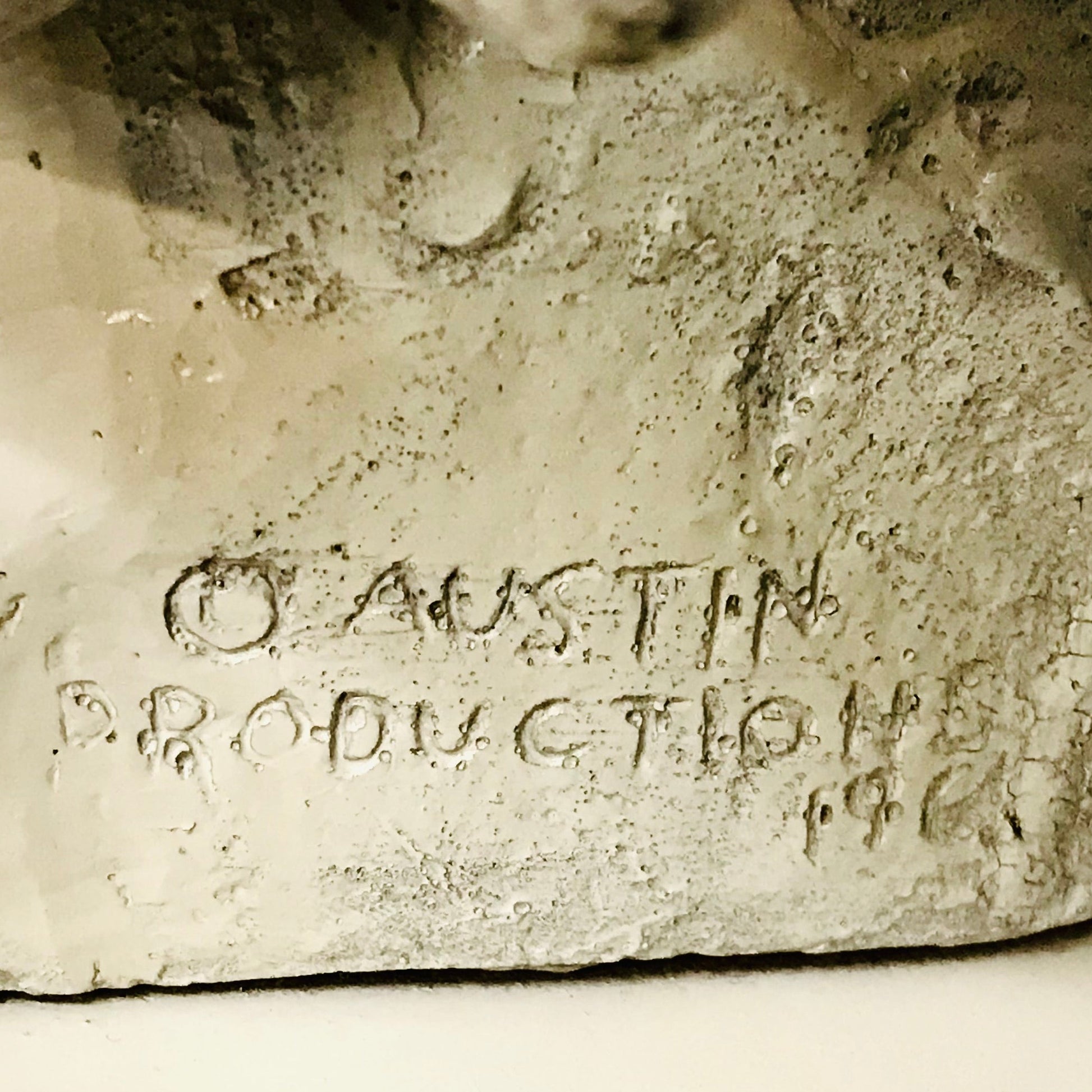 Close-up of a stone sculpture with 'O Austin Production 1968' engraved on it.