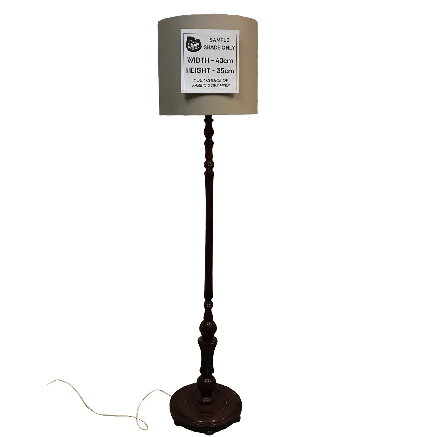 Dark wooden floor lamp with a sample size label in an indoor setting.