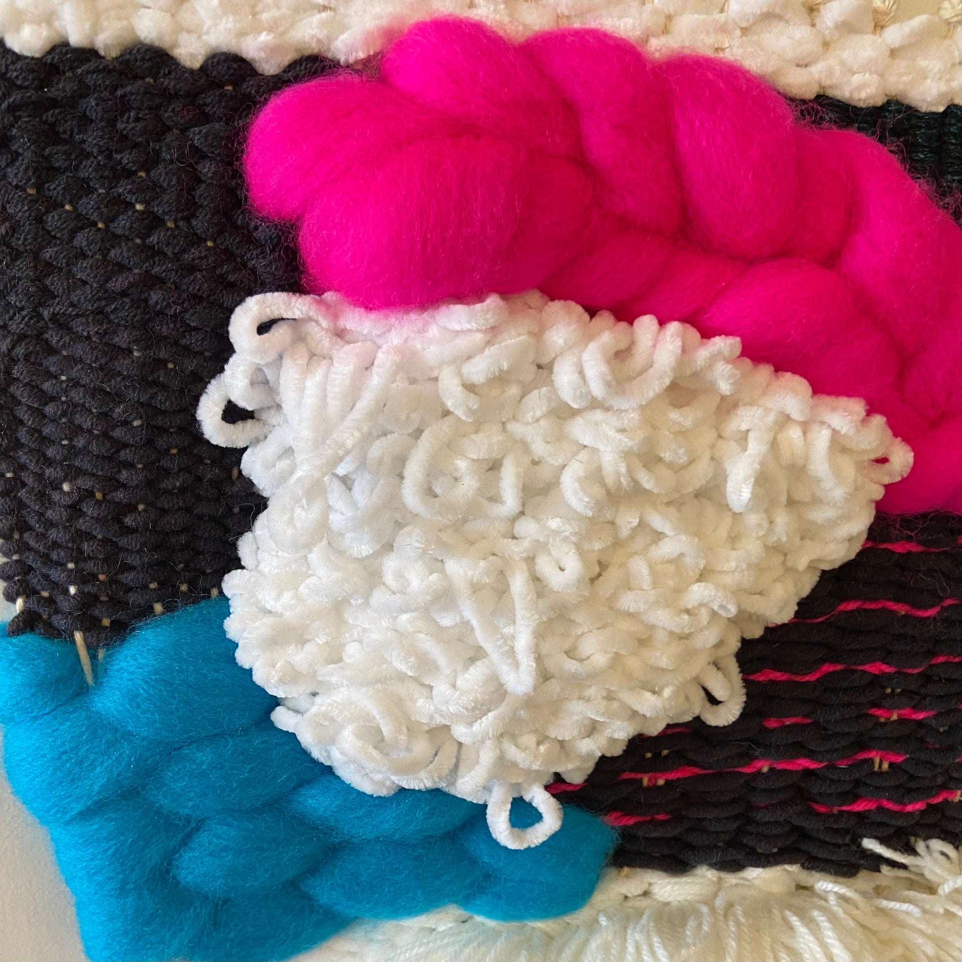Close-up of colorful yarn skeins in black, pink, white, and blue.