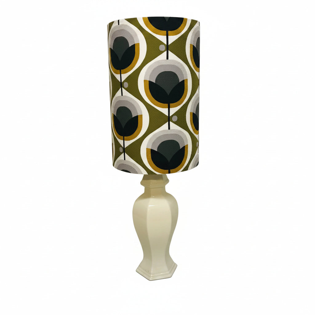 Lamp with a patterned green shade on a white base against a white wall.