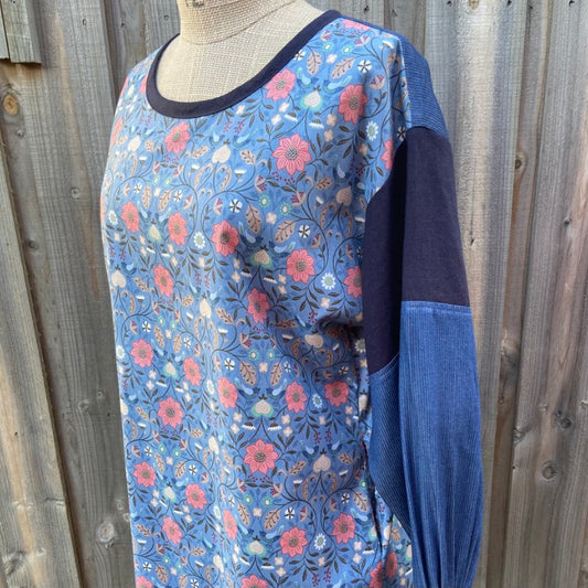 Blue floral tunic top on a mannequin against a wooden fence background