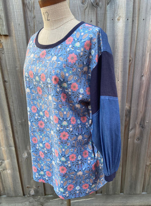 Blue floral tunic top on a mannequin against a wooden fence background