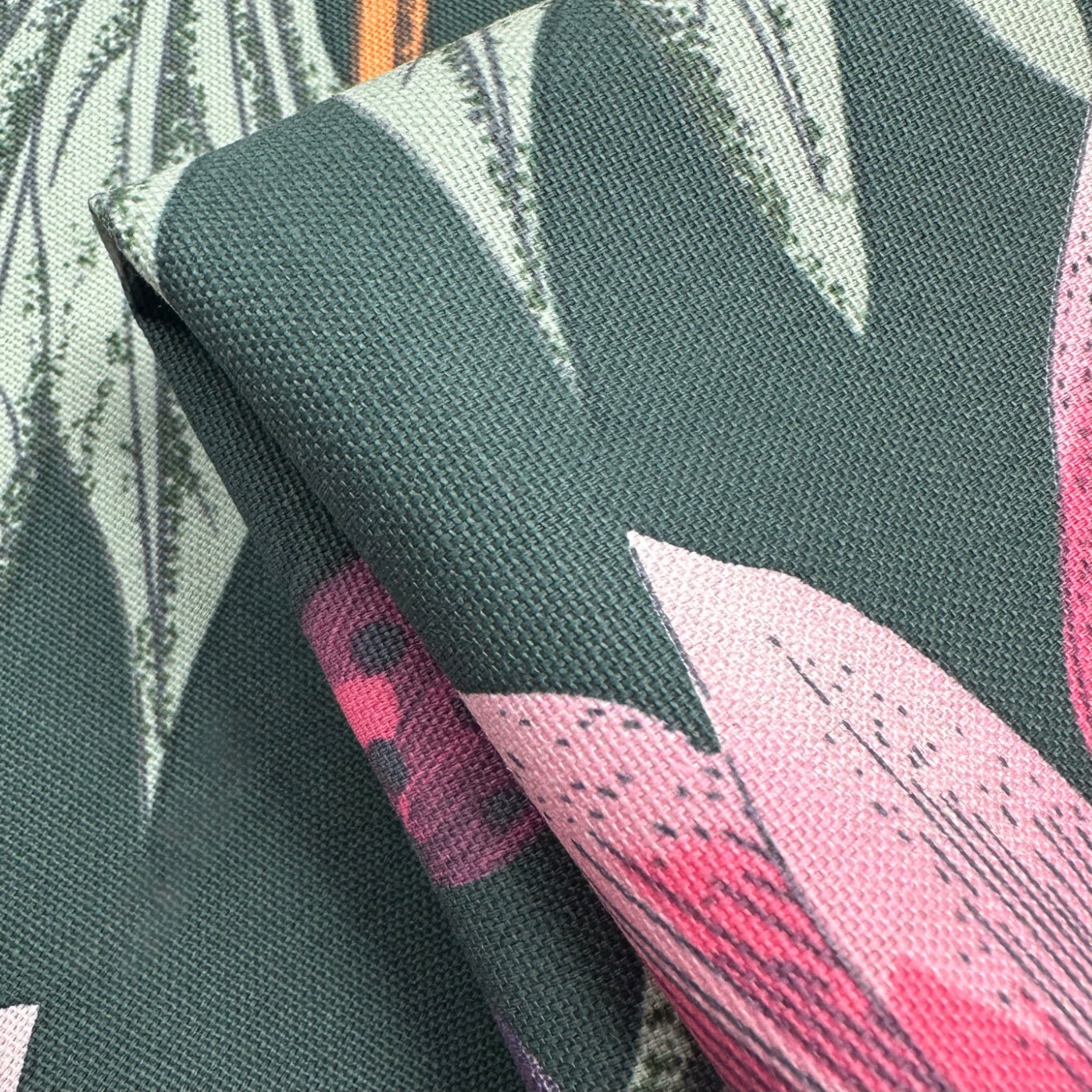 Textile with pink and white leaf pattern on a dark green background